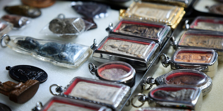 Collection of Thai Buddhist Amulets and Pendants Displayed at Market Stall