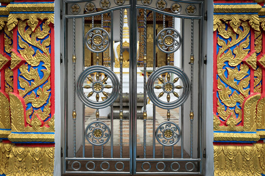 Ornate Metal Gate with Dharma Wheel Motifs and Gold Stucco Decoration at Thai Buddhist Temple