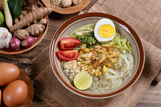 Flat lay indonesian chicken soto soup bowl with glass noodles tomato egg raw spices on rustic burlap