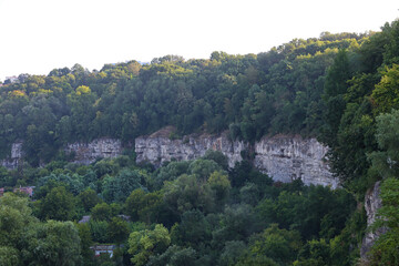Fototapeta premium Green forest and rocky cliff in a valley during the late afternoon