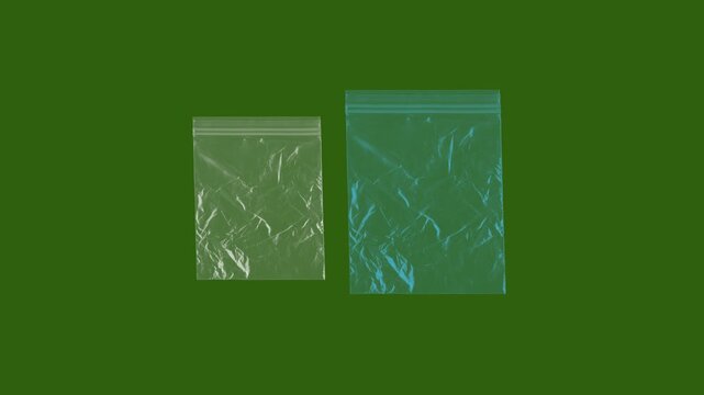 Transparent plastic zip bags on green background, clear polyethylene storage pouches, small reusable grip seal bags for packaging