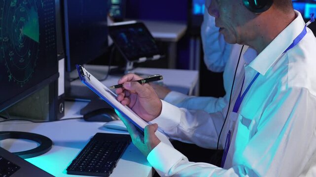 Team air traffic controller working on radar flight tracking screen in control room.