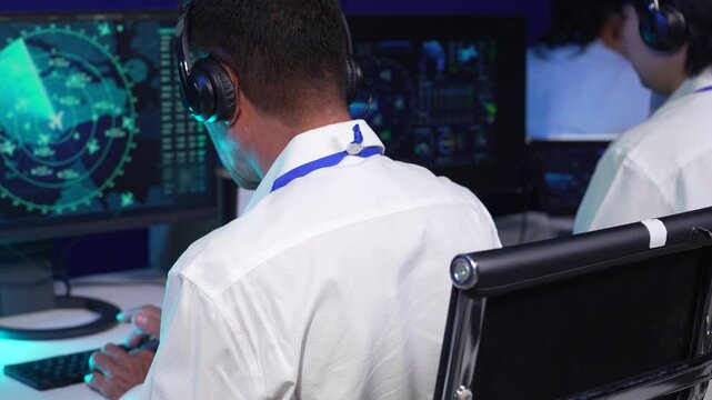 Air traffic controller monitors flight radar screens in a modern dark command center, aviation technology, flight safety, surveillance and precision.