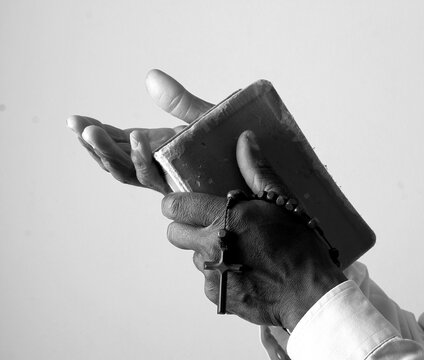 praying to god with hands showing his religious faith with God Caribbean man praying with background with people stock photo stock image	