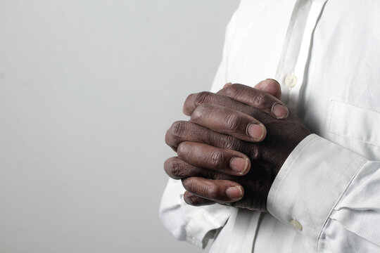 praying to god with hands showing his religious faith with God Caribbean man praying with background with people stock photo stock image	