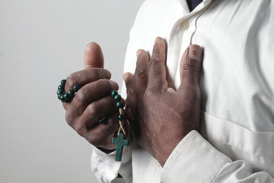 praying to god with hands showing his religious faith with God Caribbean man praying with background with people stock photo stock image	