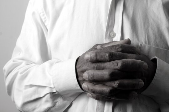 praying to god with hands showing his religious faith with God Caribbean man praying with background with people stock photo stock image	