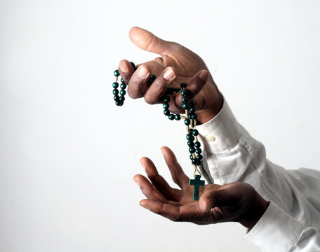 praying to god with hands showing his religious faith with God Caribbean man praying with background with people stock photo stock image	