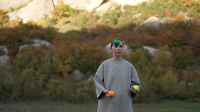 Skilled Juggling Performance Practicing Woman Throws Balls Against Autumn Mountain Backdrop