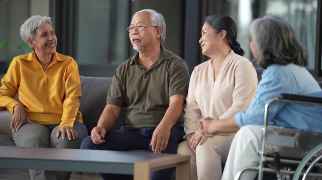 Seniors on the lounge sofa laugh and lean toward each other as one of them delivers the punchline of a story. 4K elderly care b-roll filmed in a bright Thai nursing facility.