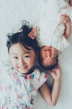 寝転がる新生児と小さなお姉ちゃん