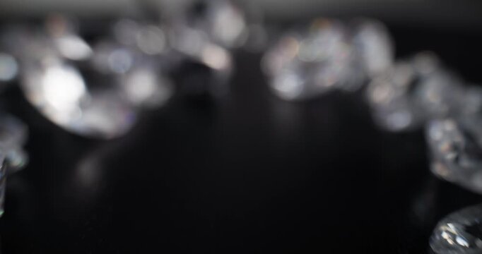 Loose diamonds being picked up with tweezers on black surface, probe lens.