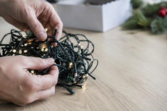 Hands Untangling Christmas Lights During Holiday Decorating