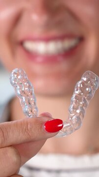 Woman Smiles While Holding Clear Dental Guards