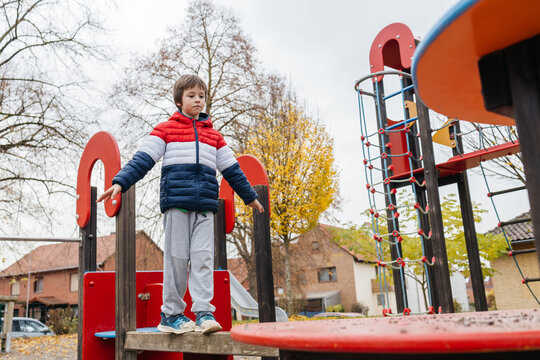 Young boy balancing on playground equipment in autumn