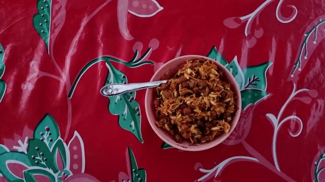 Spicy indian street food snack jhalmuri served in a pink bowl on red floral tablecloth