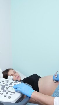 Pregnant woman receiving a fetal ultrasound scan from an obstetrician in a hospital room, a medical professional using a transducer to monitor the baby's health during a prenatal check up
