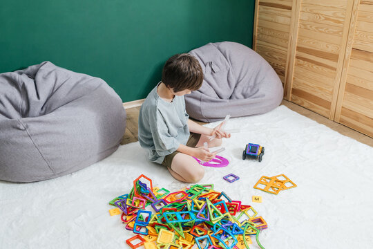 Boy playing with magnetic building blocks on a rug