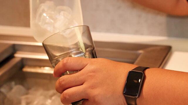 Scooping Ice Cubes into a Glass at a Hotel Beverage Station