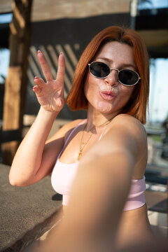 Redhead woman taking selfie showing peace sign