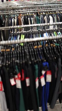 Vertical screen rows of clothing racks filled with autumn jackets sweaters and casual garments create a dense fashion selection inside a bright modern retail store spaces