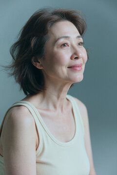 Portrait of senior Asian woman gazing upward and smiling, expressing confidence, healthy aging, positive mindset. Ideal for wellness, skincare, retirement, lifestyle marketing