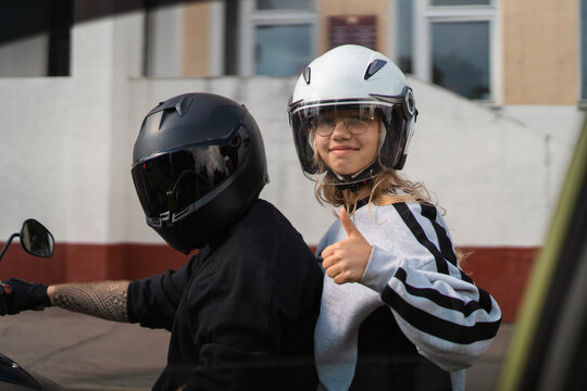 Girl gives thumbs up on back of motorcycle