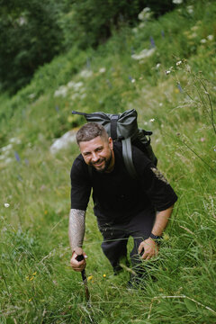 Cheerful tattooed man enjoys a hike in nature