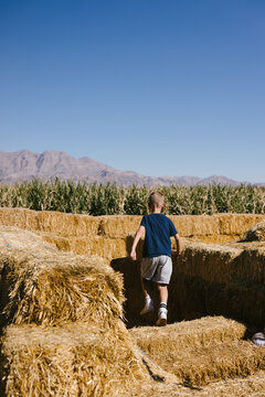 Young boy exploring a large hay bale maze outdoors