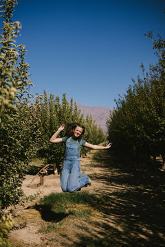 Carefree young girl jumps high in a sunny orchard