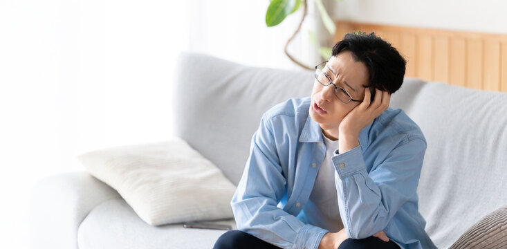 リビングのソファに座って考える男性
