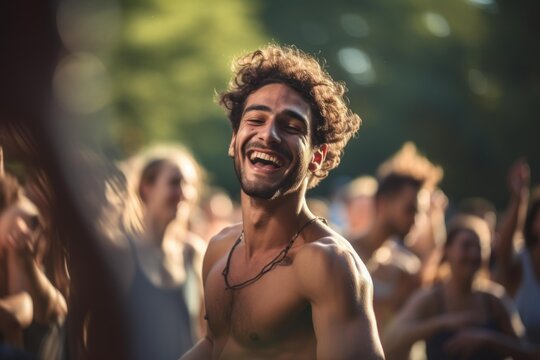 Young man laughing wholeheartedly during an outdoor music event with people in background