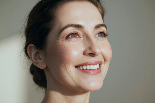 Close up of Caucasian middle aged woman smiling and looking away, expressing confidence and healthy aging. Ideal for skincare, wellness, dental care, beauty campaign use