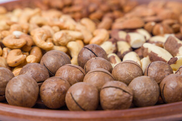 Fototapeta premium Macadamia nuts in a bowl on a wooden table. Selective focus.