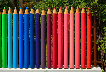 Fototapeta premium kolorowe pasy, tęczowe prążki, kolorowe kredki z drewna, ogrodzenie w formie kolorowych kredek z drewnianych bali, rainbow stripes, fence made of wooden logs shaped like colorful crayons