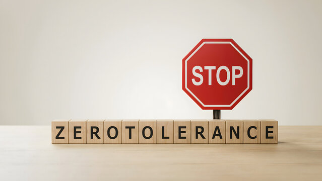 Wooden blocks spelling zero tolerance with a red stop sign on a wooden table