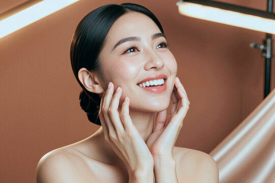 Close up of Asian young adult woman touching face and smiling, presenting skincare results and beauty wellness concept. Ideal for cosmetic advertising, spa branding, skincare campaigns