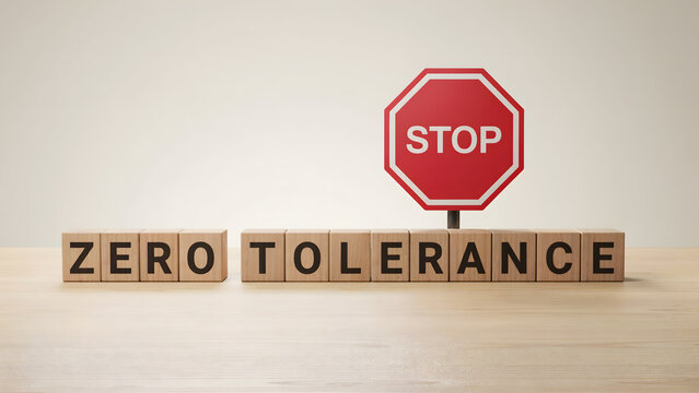 Wooden blocks spelling zero tolerance with a red stop sign on a wooden table