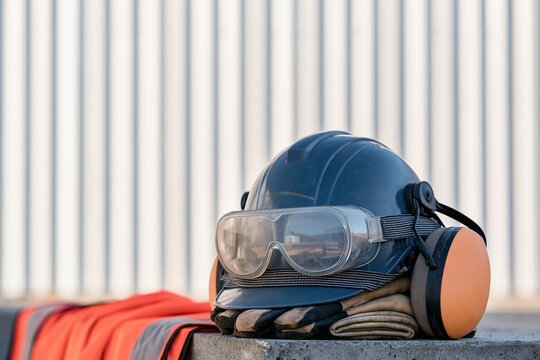Grey construction safety helmet with protective gear on folded work gloves, featuring a scuffed texture and dust for occupational safety marketing