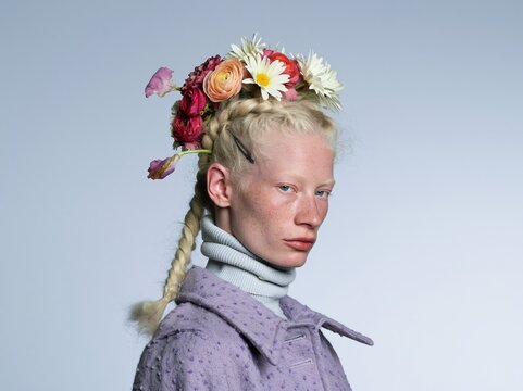 Woman wearing a floral crown of roses and daisies, featuring a soft purple coat and ribbed turtleneck for floral fashion and beauty branding