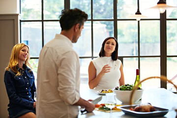 Fototapeta premium Cooking, kitchen and man with friends for wine, conversation and culinary lesson in home. Bonding, social reunion and people together with lunch, discussion and drink for learning recipes in house