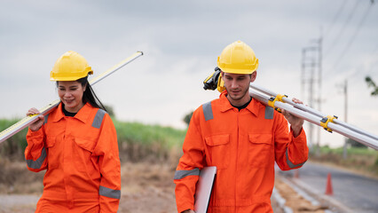 Civil engineers and survey team using a total station theodolite and road construction plans to...