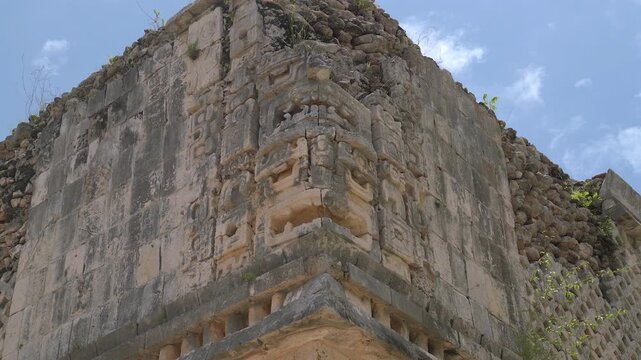 Static low angle corner shot of carved Chaac god masks on the stone facade of an ancient Mayan building at Uxmal archaeological site in Yucatan, Mexico.