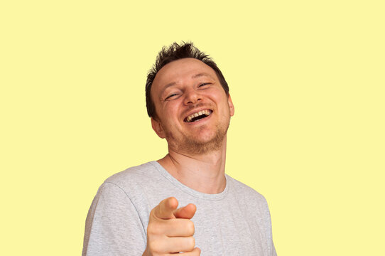 Man laughing heartily and pointing finger at viewer with joy