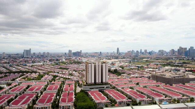 Aerial panorama of Peng Huoth Boeung Snor in Chbar Ampov, Phnom Penh, showing dense red-roof housing, a residential tower and the expanding Cambodian capital skyline.