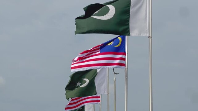 Pakistan Malaysia Flags Flying Side by Side Against Cloudy Sky Background