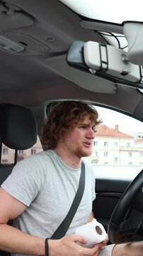 Vertical screen motorist clutches his stomach and holds toilet paper inside the car showing severe bathroom urgency while desperately trying to locate a restroom downtown