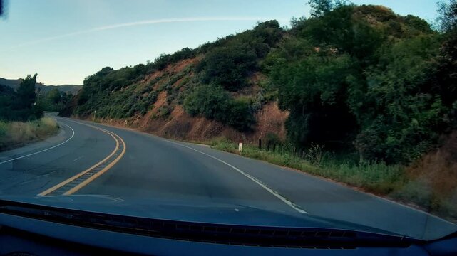 Dashcam Cold Canyon Rd vehicle perspective journey on winding mountain road with natural landscape, green foliage along hills, clear sky and open highway conditions.