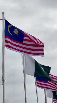 Pakistan and Malaysia National Flags Waving Together Under Cloudy Sky, International Relations, Seamless Loop