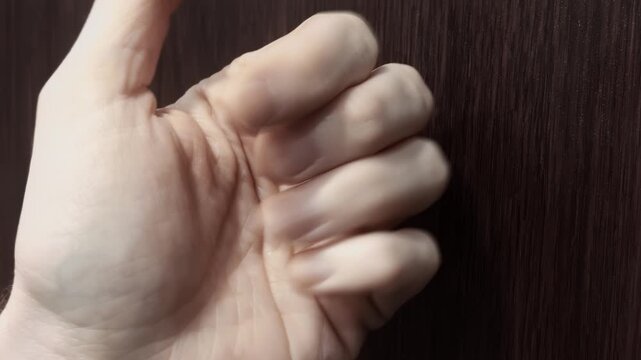 Knuckles bang on front door. Close up view male hand knocking wood door surface. Person knuckles repeatedly strike wooden panel. Urgent entry request.